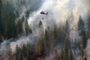 helicopter flying through burning forest