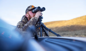 man scoping out with binoculars