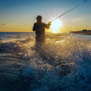 Angler casting in the surf.