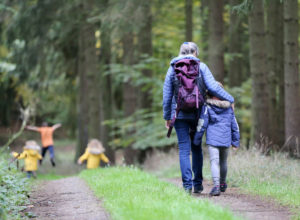 Grandmother with grandchildren hiking in a forest.